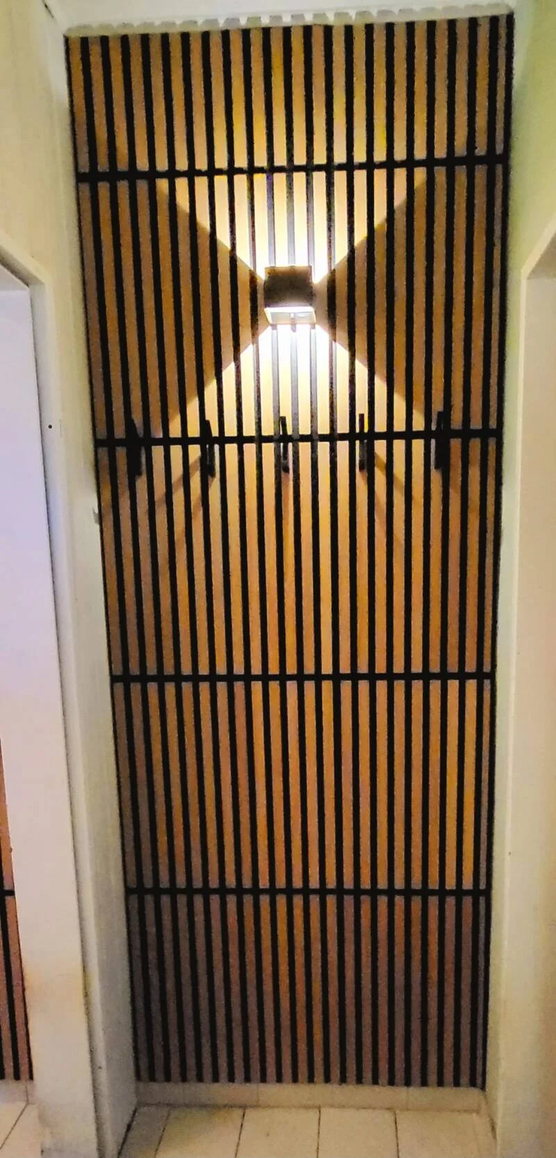 Wandverkleidung mit schwarzen Leisten und Beleuchtung
